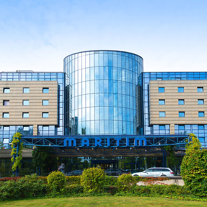 Außenansicht des Maritim Hotels Bonn mit moderner Glasfassade und gepflegter Gartenanlage im Vordergrund.