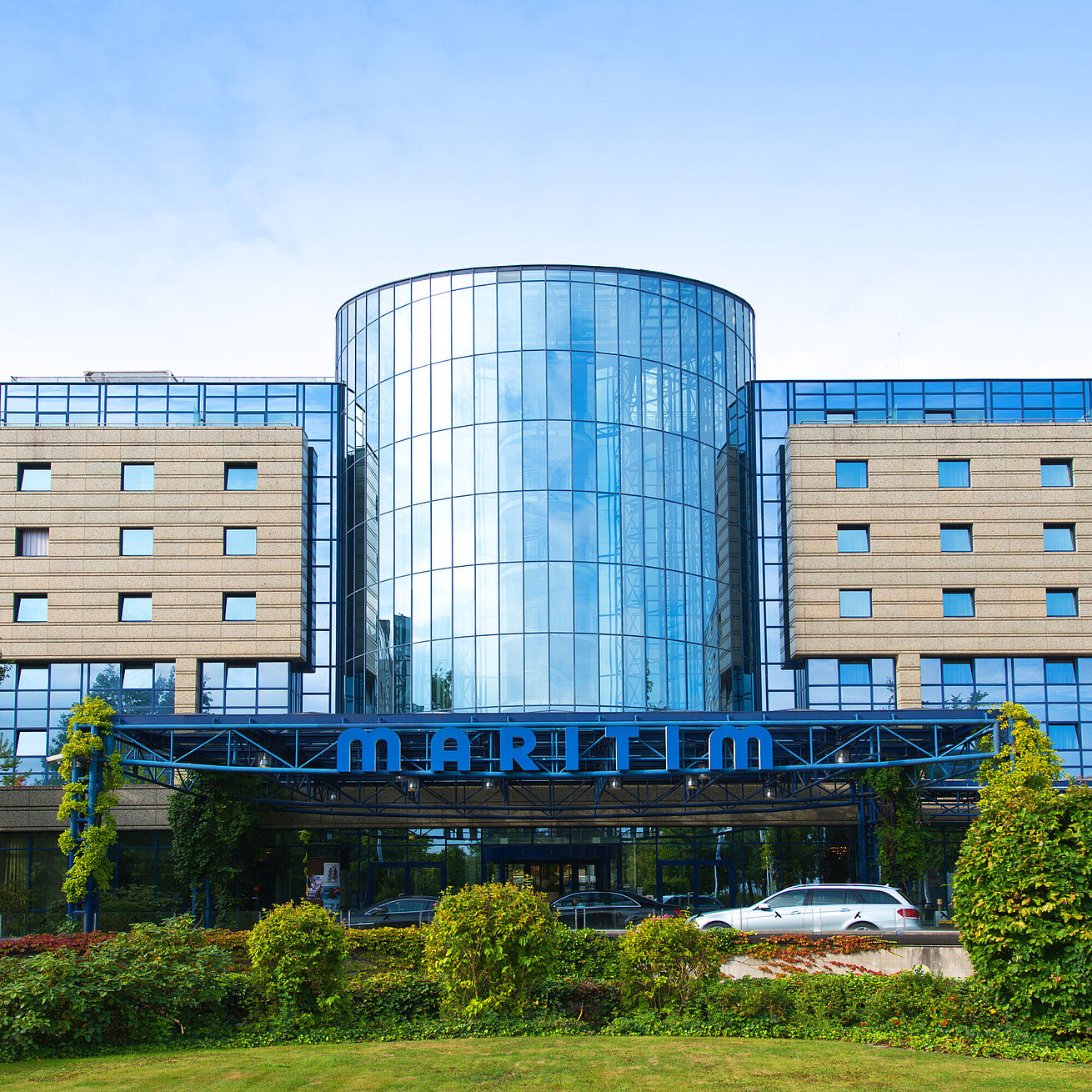 Außenansicht des Maritim Hotels Bonn mit moderner Glasfassade und gepflegter Gartenanlage im Vordergrund.