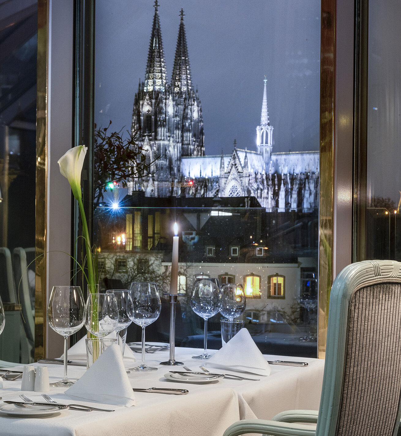 Blick auf den Kölner Dom durch das Fenster des Restaurants "Bellevue" im Maritim Hotel Köln, gedeckter Tisch im Vordergrund.