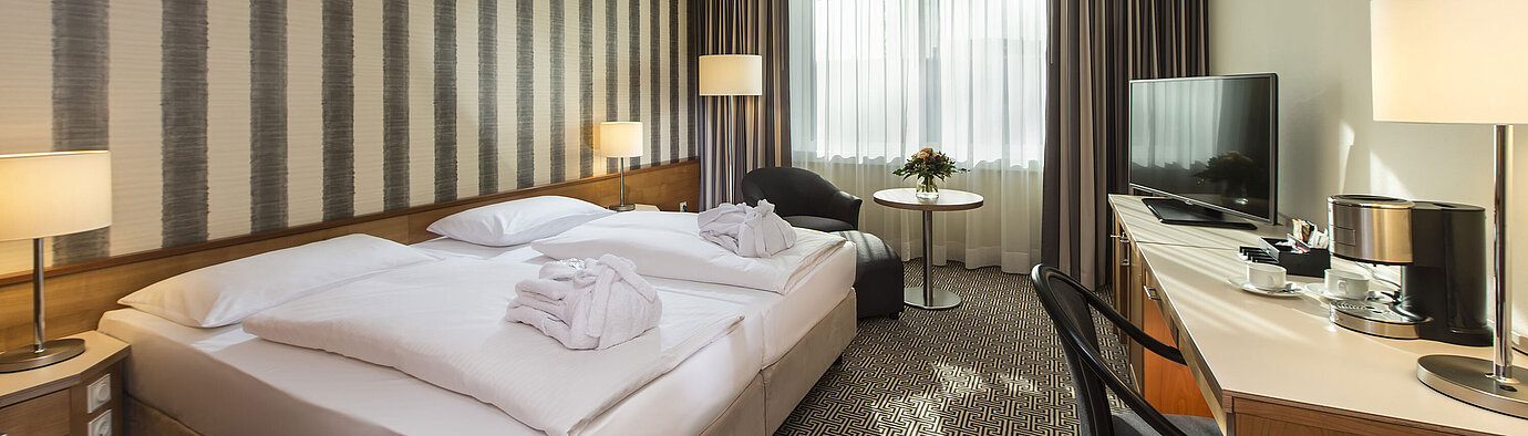 Helles Doppelzimmer mit Schreibtisch, Sesseln und großem Bett im Maritim Hotel Stuttgart