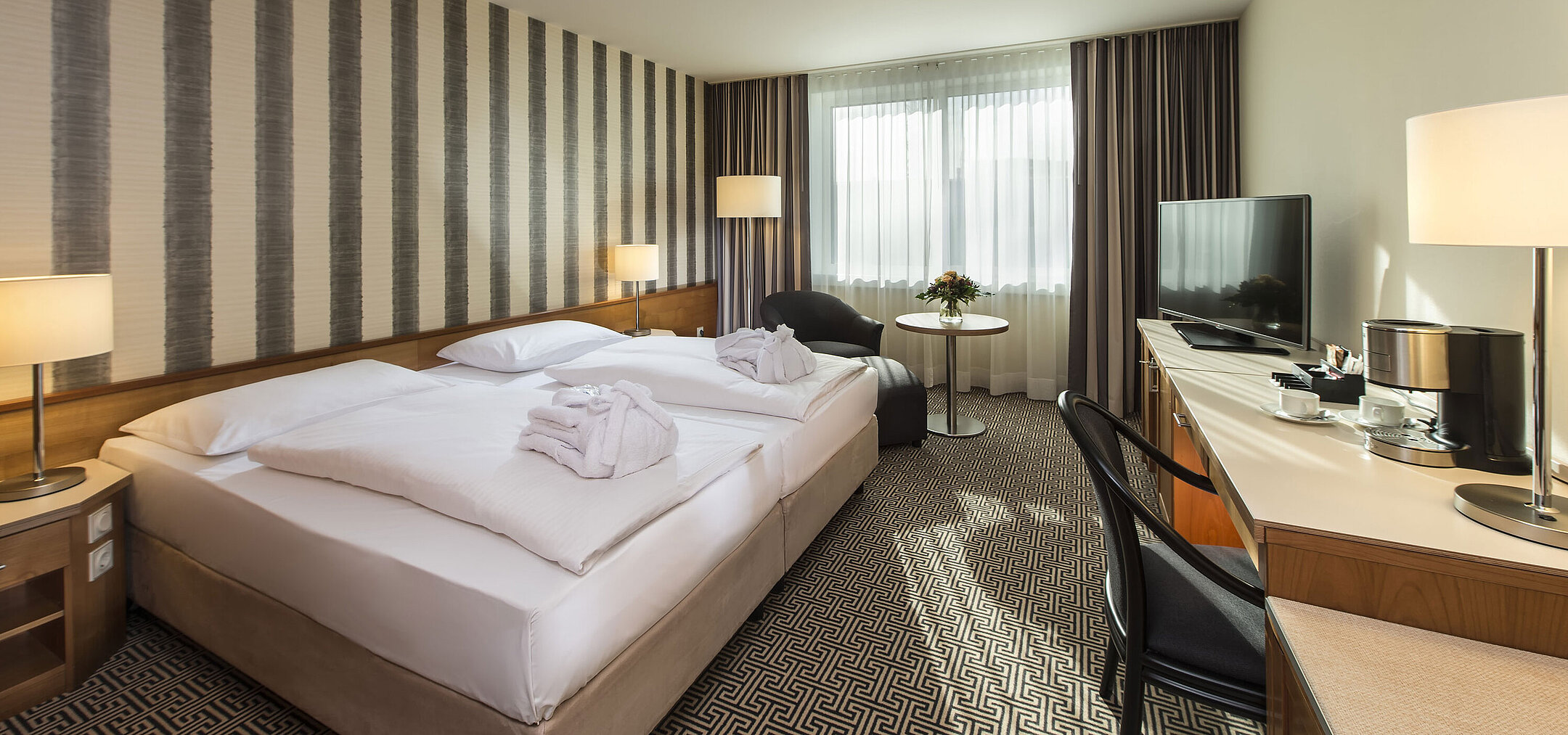 Helles Doppelzimmer mit Schreibtisch, Sesseln und großem Bett im Maritim Hotel Stuttgart