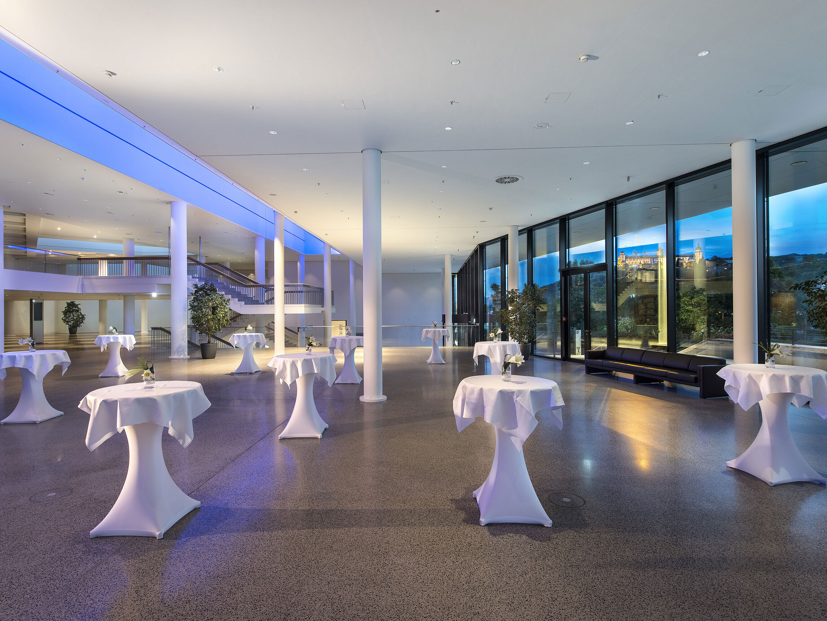 Modernes Foyer im Maritim Hotel Würzburg mit Stehtischen, großer Fensterfront und Blick auf die Festung