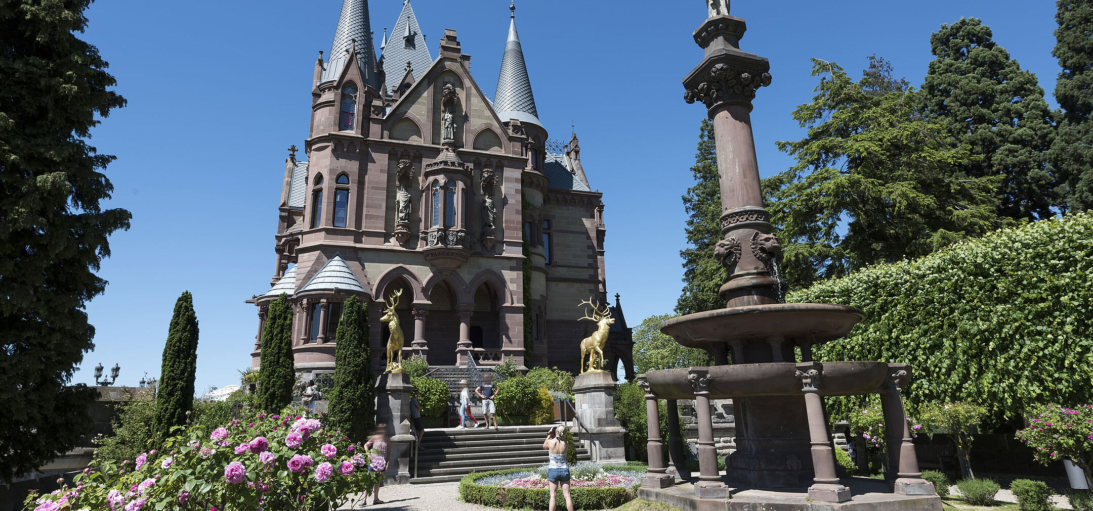 Das prachtvolle Schloss Drachenburg mit einem kunstvollen Brunnen und blühendem Garten.