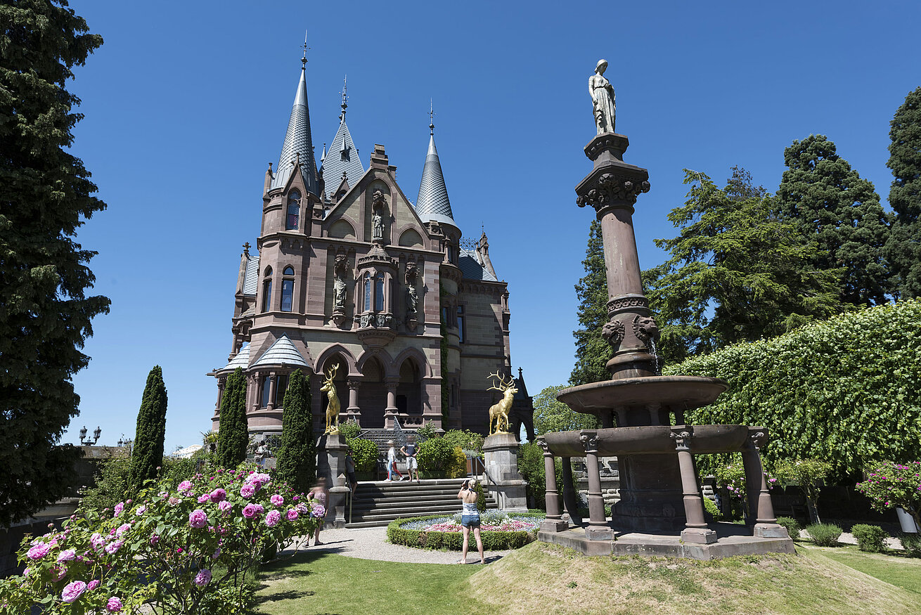 Das prachtvolle Schloss Drachenburg mit einem kunstvollen Brunnen und blühendem Garten.