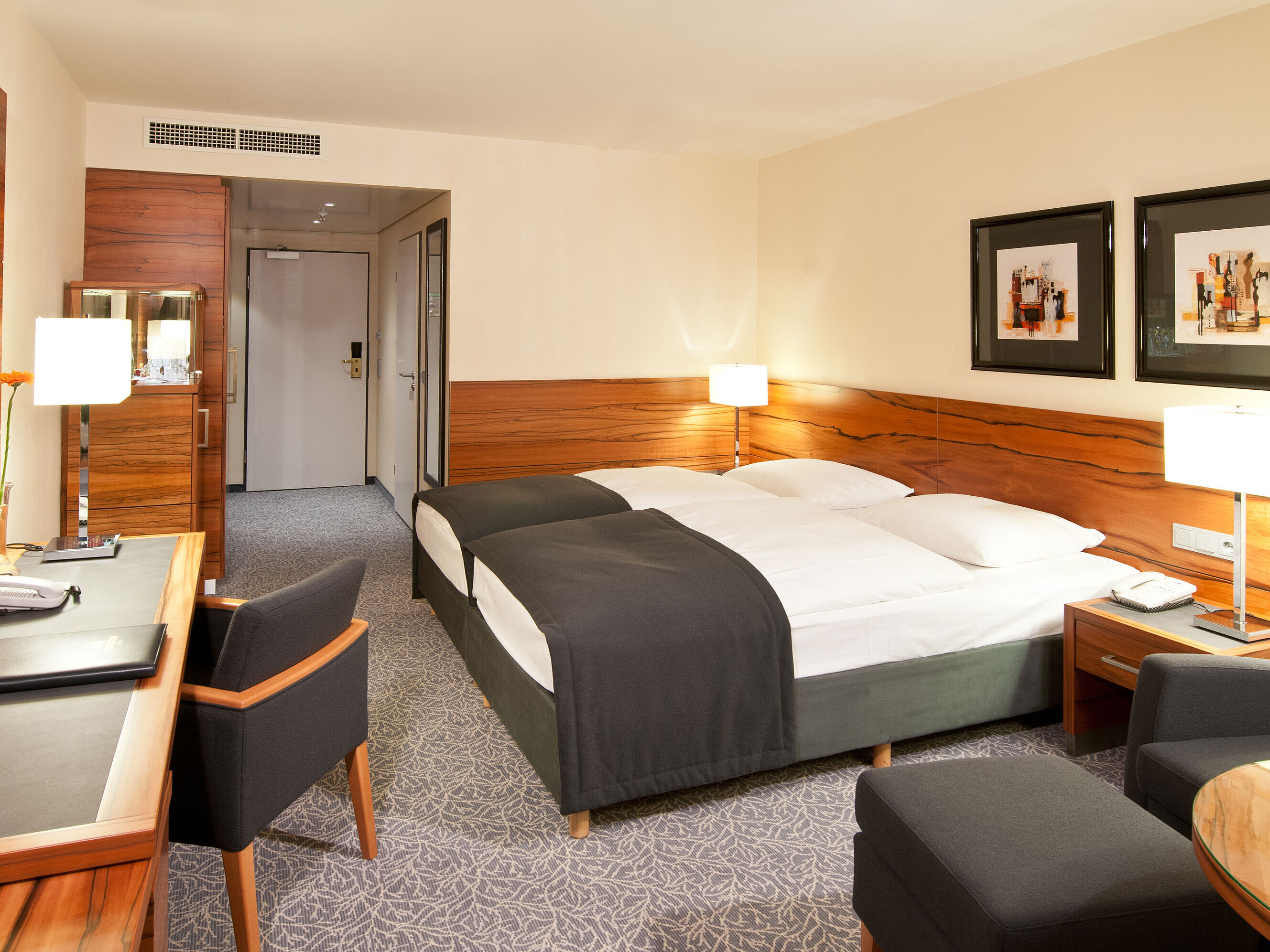 Doppelzimmer mit Holzdetails, Sitzgruppe und Schreibtisch im Maritim Hotel München