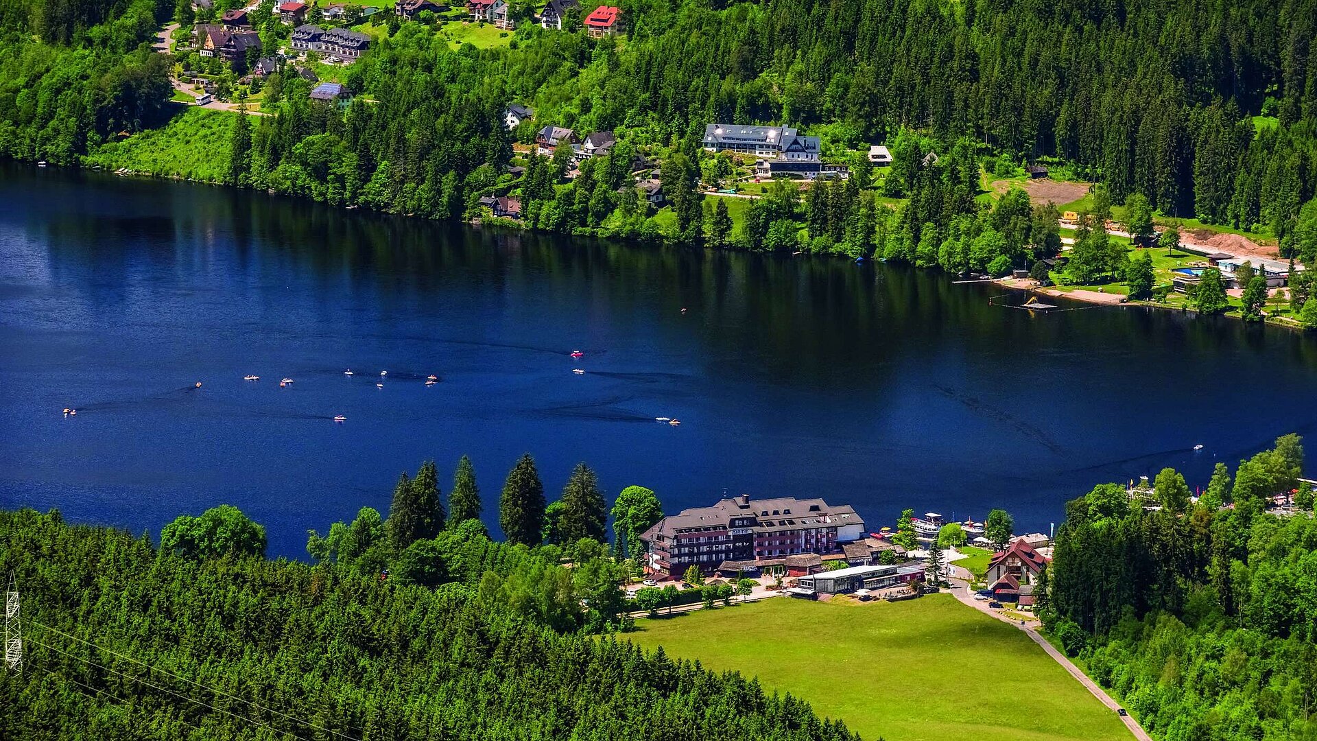 Vogelperspektive Luftaufnahme des Maritim Hotels direkt am Ufer des Titisees mit umliegendem Wald und Tretbooten auf dem Wasser