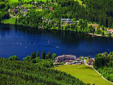 Luftaufnahme des Maritim Hotels direkt am Ufer des Titisees mit umliegendem Wald und Tretbooten auf dem Wasser