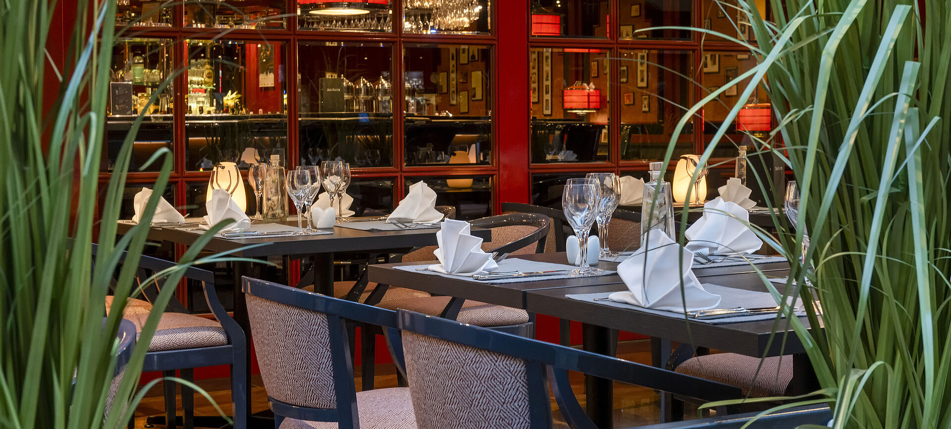 Stilvoll gedecktes Bistro im Maritim Hotel Magdeburg mit freundlicher Mitarbeiterin, die Tische vorbereitet.