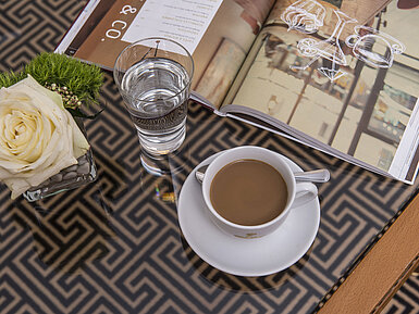 Nahaufnahme mit Rose, Kaffee, Wasser und Magazin auf Glastisch im Maritim Hotel Stuttgart