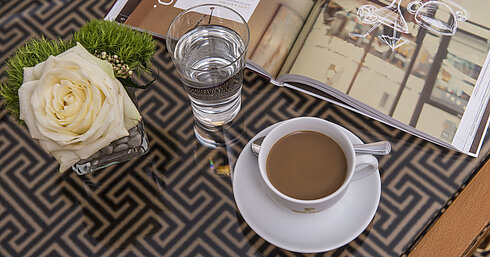 Nahaufnahme mit Rose, Kaffee, Wasser und Magazin auf Glastisch im Maritim Hotel Stuttgart
