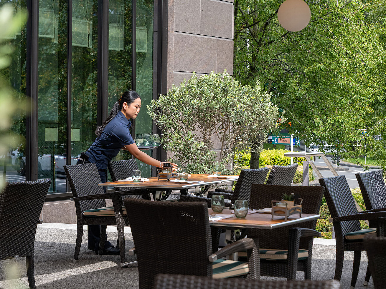 Terrasse Mitarbeiterin deckt die Terrasse mit Sitzplätzen im Maritim Hotel Düsseldorf ein