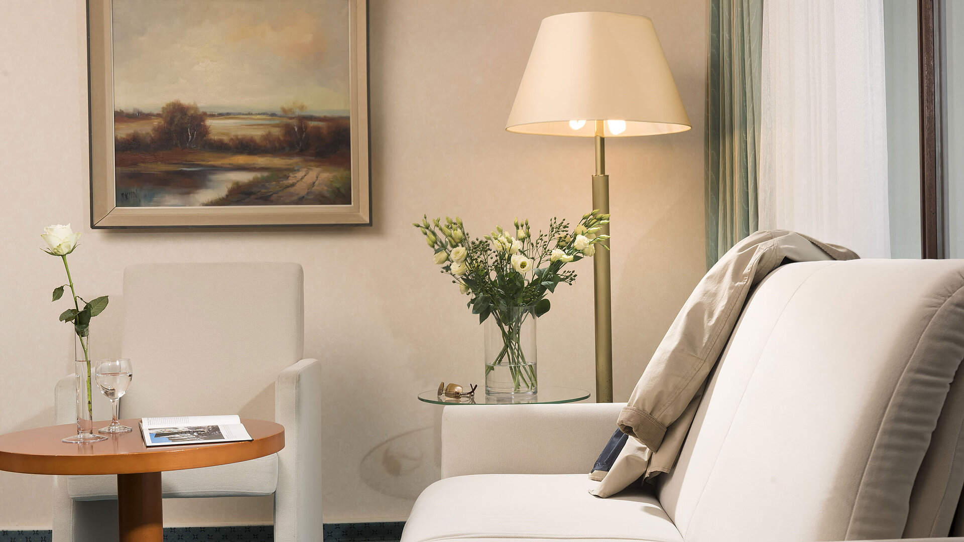 Junior Suite Heller Wohnbereich im Maritim Hotel Bad Salzuflen mit Blumen, Gemälde und gemütlicher Sitzgruppe