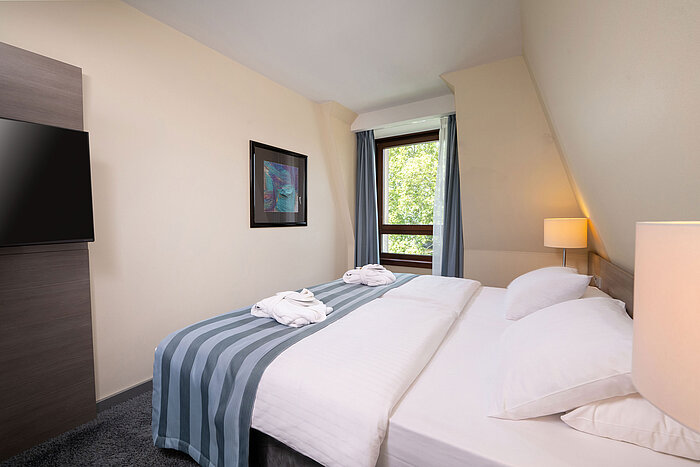 Schlafzimmer der Junior Suite im Maritim Hotel Königswinter mit Doppelbett, Fenster und hellem Ambiente.