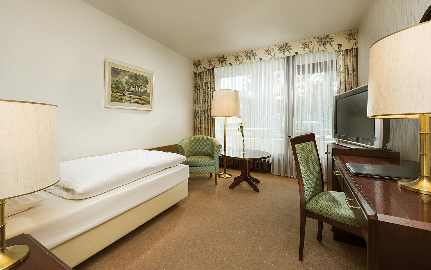 Einzelzimmer mit Schreibtisch, Sessel und Balkonzugang im Maritim Hotel Bad Salzuflen