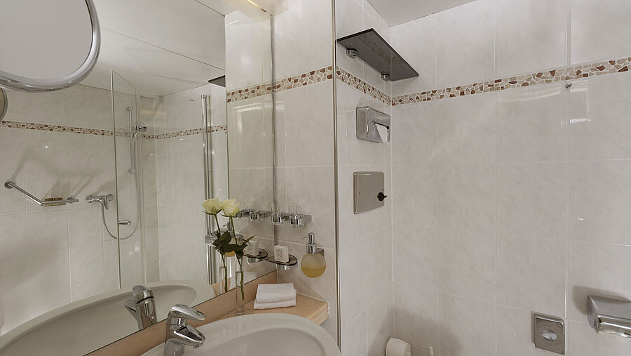 Helles Bad im Maritim Hotel Bad Salzuflen mit Dusche, großem Spiegel und weißen Fliesen