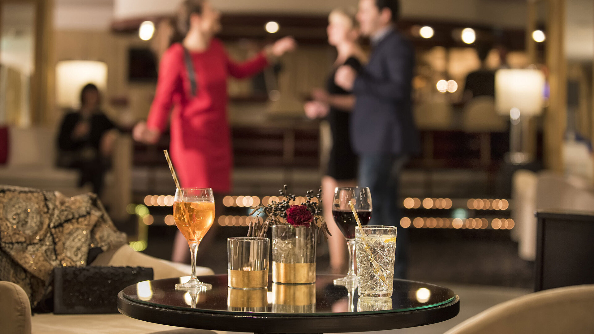 73Bar Tisch mit Cocktails und Drinks, während Gäste in der Bar des Maritim Seehotel Timmendorfer Strand tanzen.