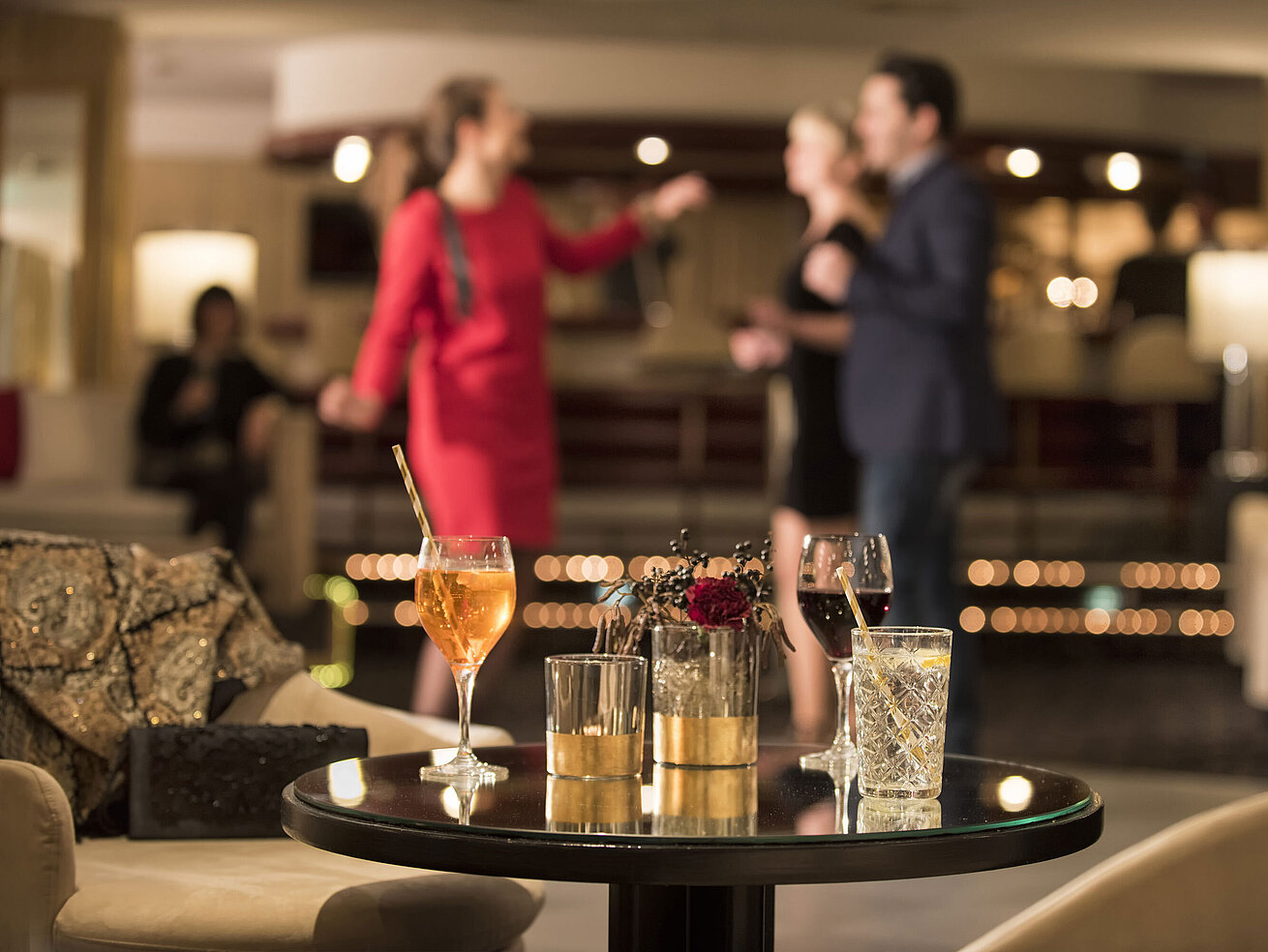 Tisch mit Cocktails und Drinks, während Gäste in der Bar des Maritim Seehotel Timmendorfer Strand tanzen.