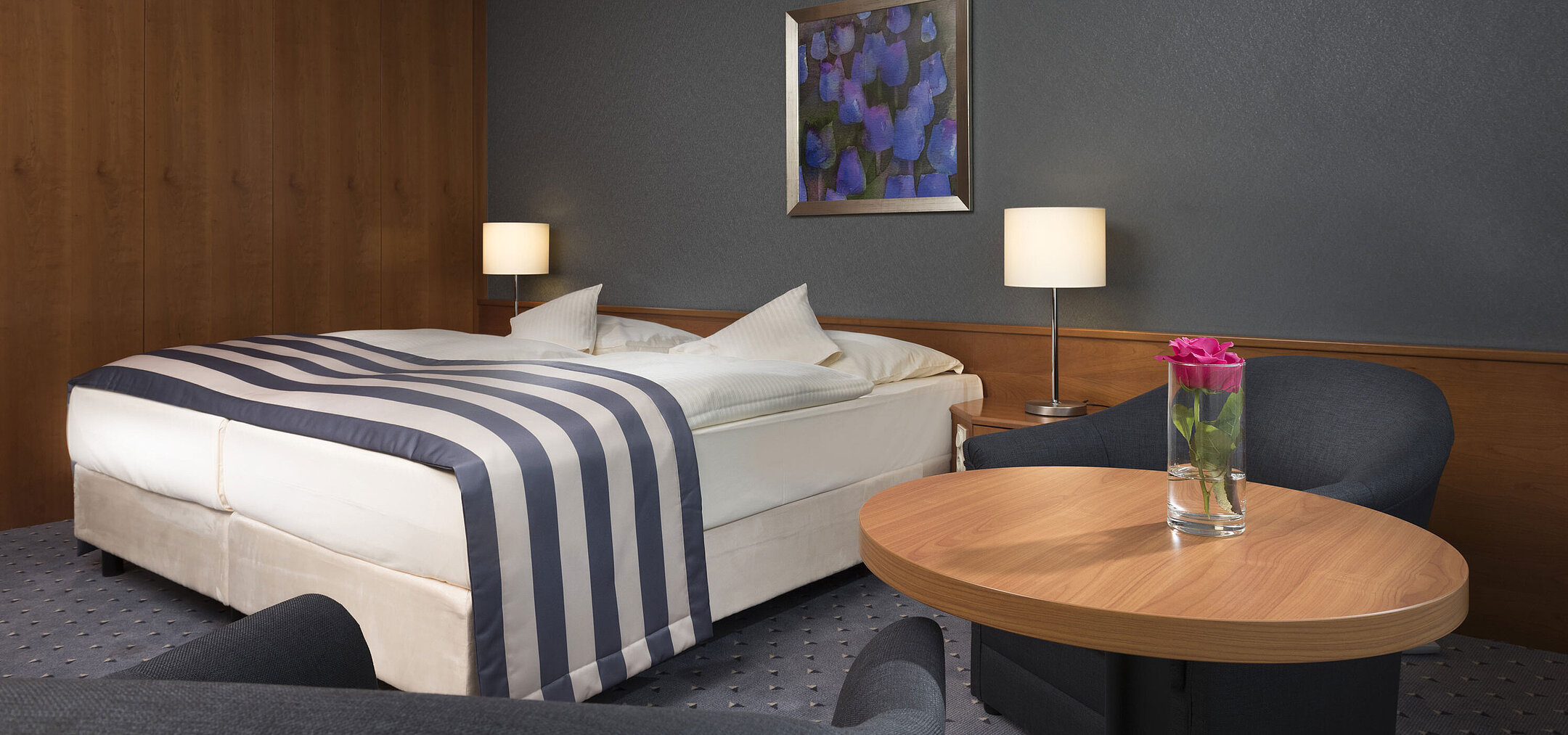 Gemütliches Doppelzimmer im Maritim Hotel Ulm mit Sitzecke, Holzverkleidung und frischer Rose
