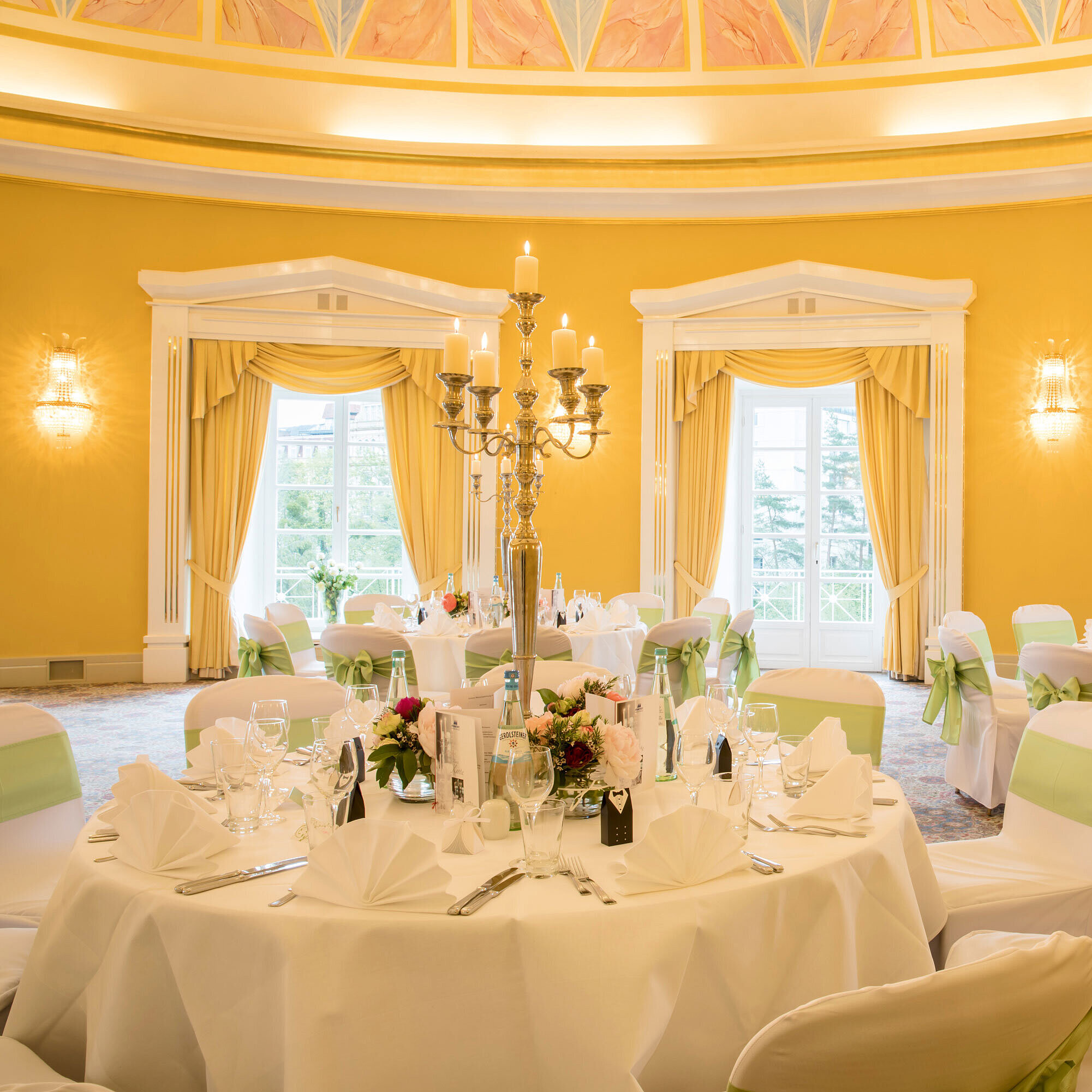 Festlich gedeckter Saal mit weißen Hussen und grünen Schleifen für Hochzeiten im Maritim Hotel Bad Wildungen