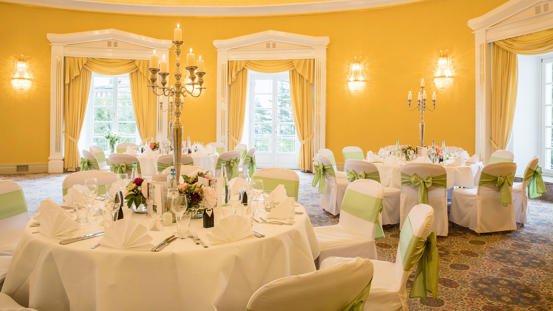 Festlich gedeckter Saal mit weißen Hussen und grünen Schleifen für Hochzeiten im Maritim Hotel Bad Wildungen