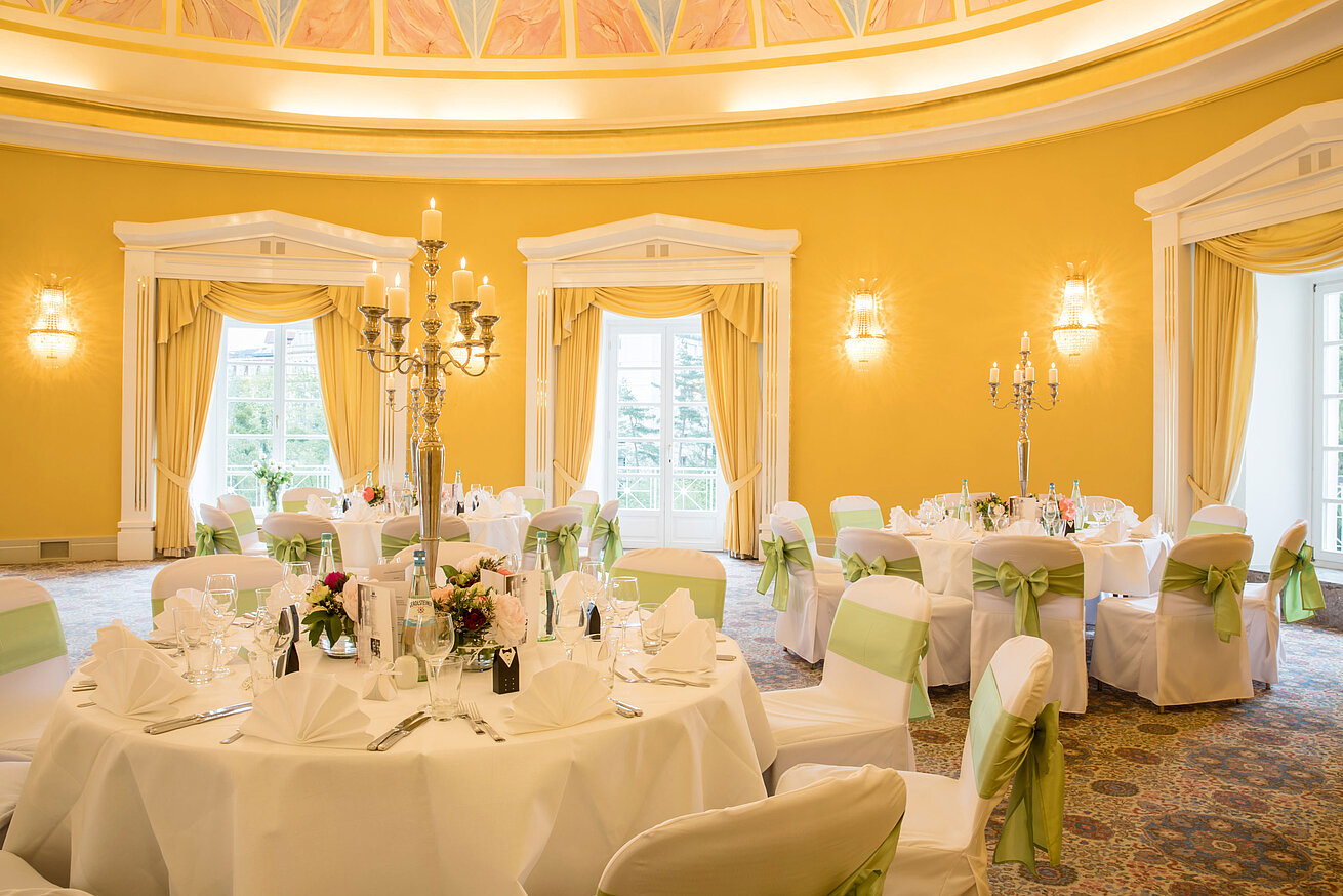Festlich gedeckter Saal mit weißen Hussen und grünen Schleifen für Hochzeiten im Maritim Hotel Bad Wildungen