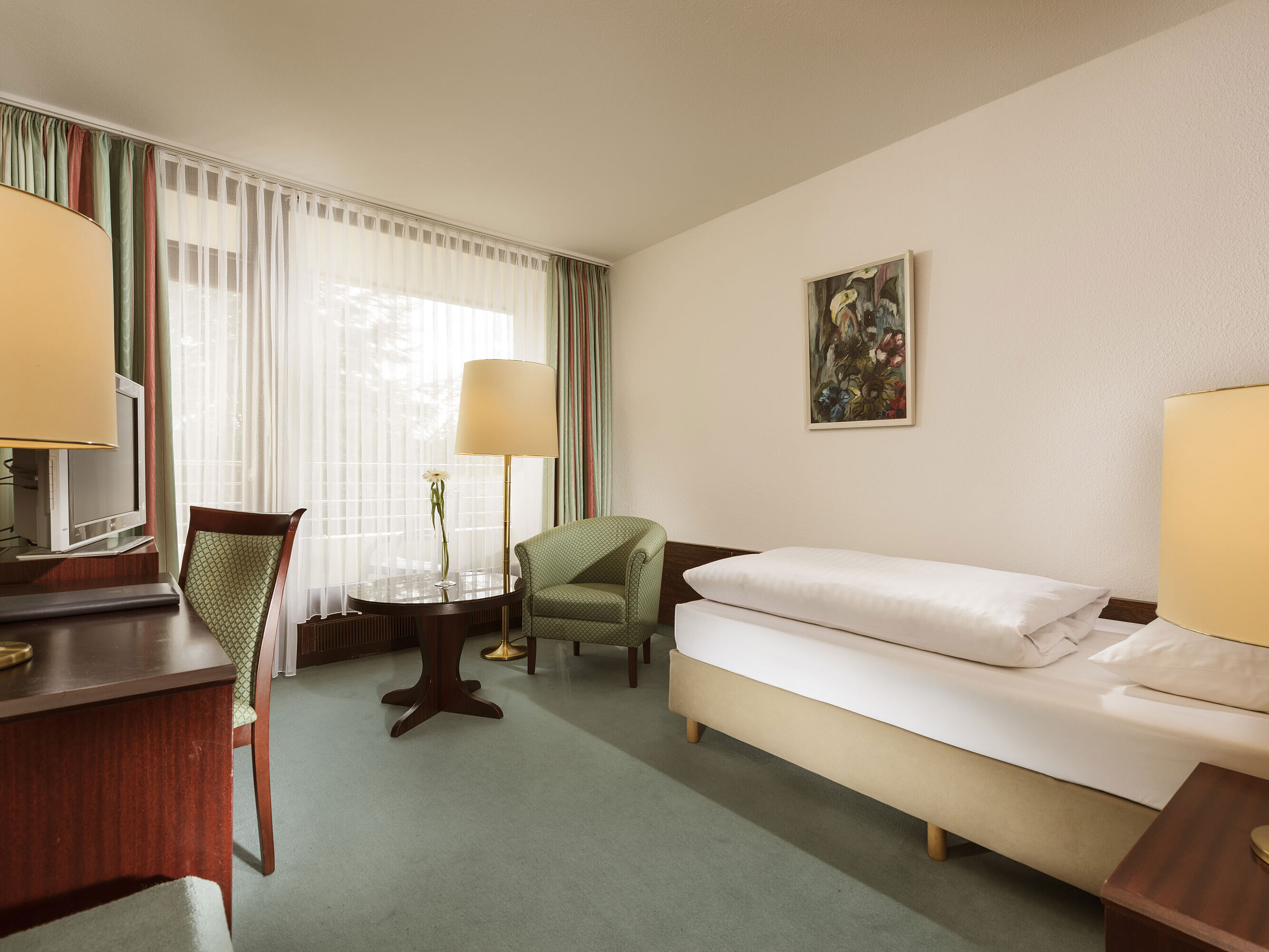 Freundliches Einzelzimmer mit Sessel, Schreibtisch und großem Fenster im Maritim Hotel Bad Salzuflen