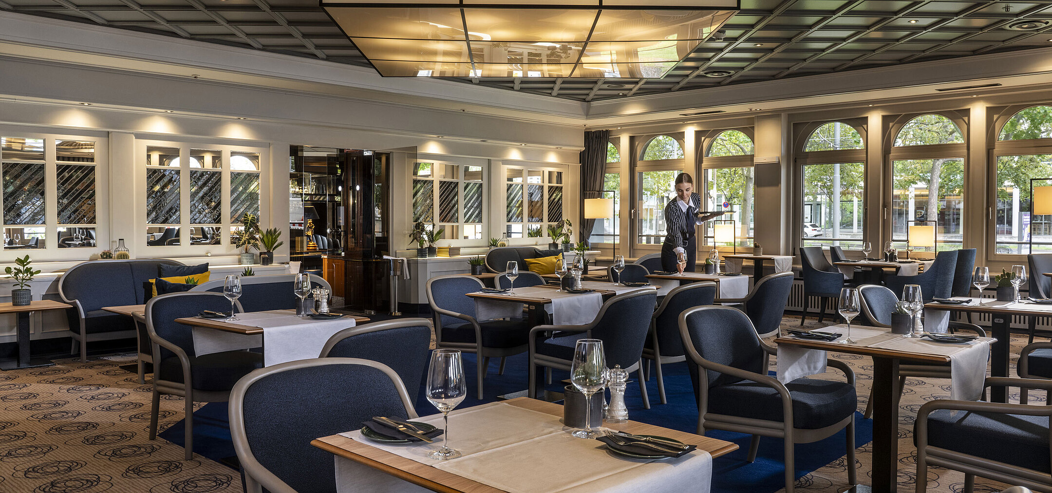 Lounge Restaurant Modernes Restaurant im Maritim Darmstadt mit gedeckten Tischen und elegantem Design. Eine Mitarbeiterin sorgt für den Service