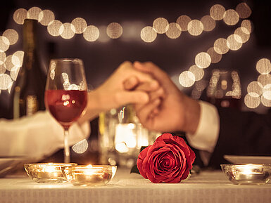 © kieferpix - AdobeStock.com Romantisches Candle-Light-Dinner mit Rotwein, Rosen und Kerzenschein
