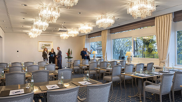 Der Salon Kopenhagen im Maritim Hotel Kiel, ein eleganter Konferenzraum mit Kronleuchtern, gedeckten Tischen und großen Fenstern.