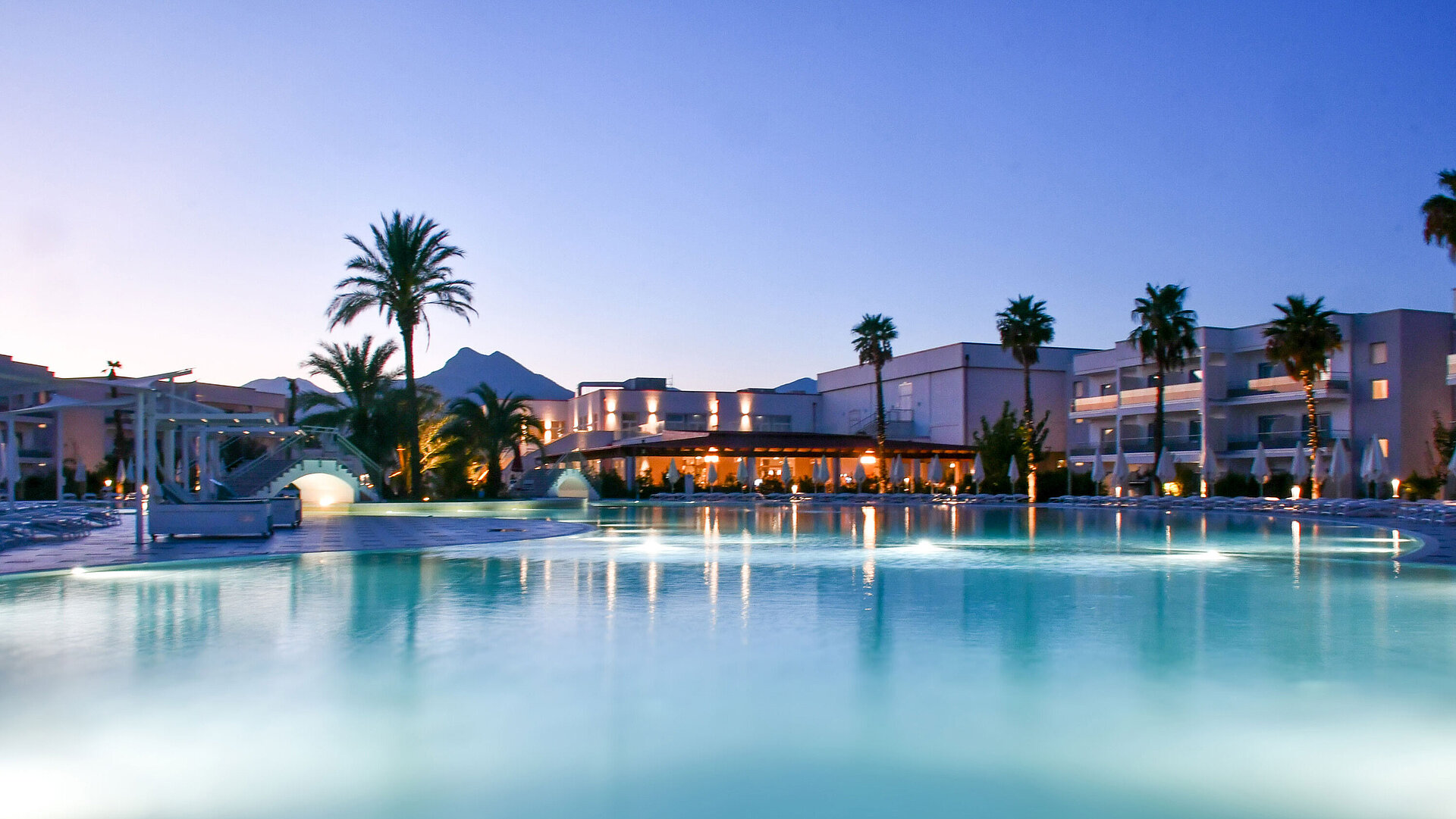 Schwimmbad Poolbeleuchtung am Abend im Maritim Resort Calabria mit Palmen und Gebirgskulisse