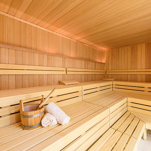 Gemütliche Sauna im Wellnessbereich des Maritim Hotels Bremen mit Holzbänken, Saunaeimer und Handtuch, ideal zur Entspannung.