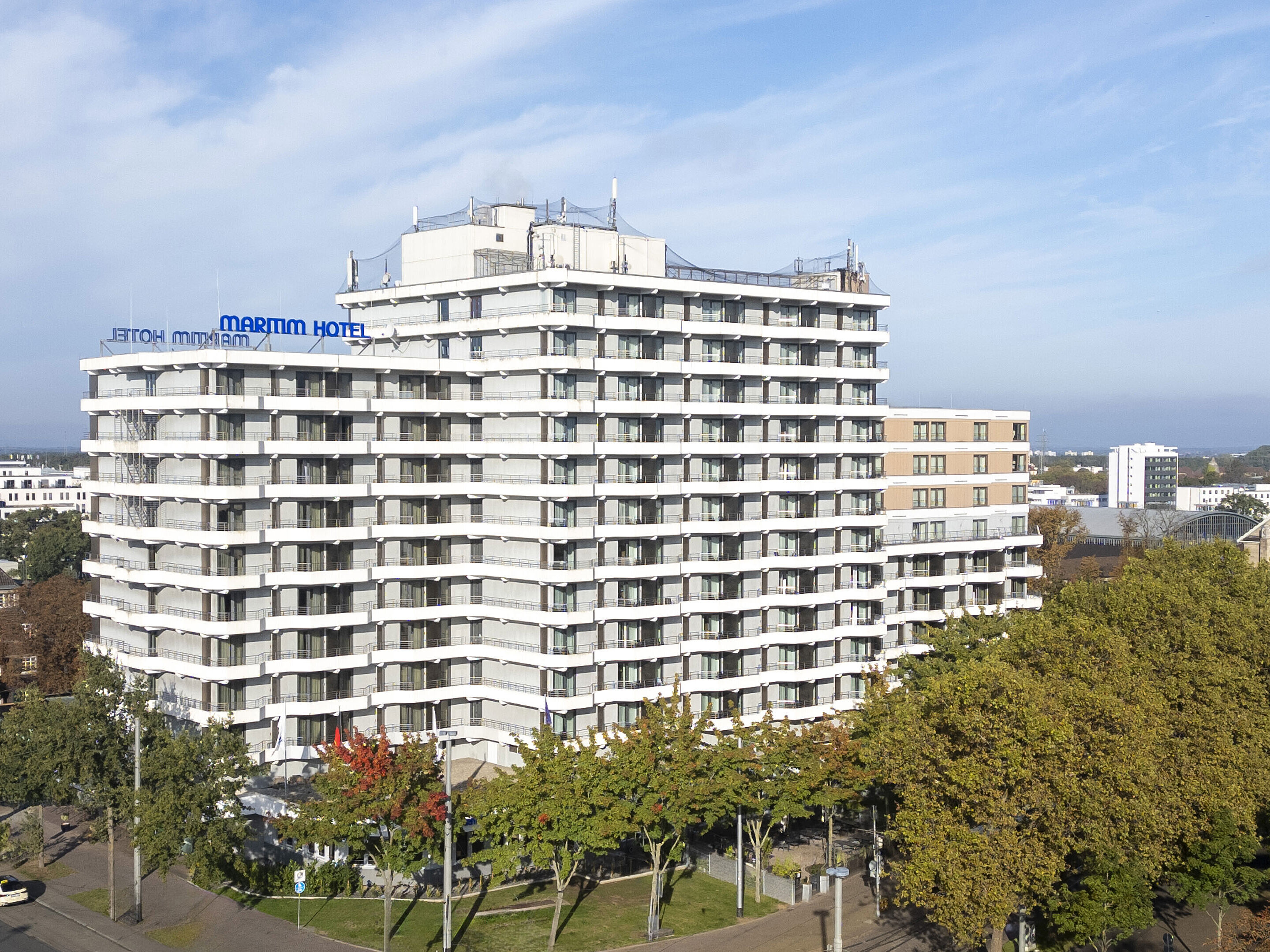 Außenansicht des Maritim Hotel Darmstadt mit moderner Architektur und grünen Bäumen im Vordergrund.