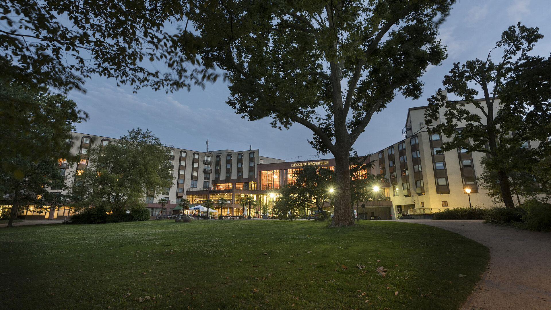 Außenansicht Kongresscenter Blick auf das Maritim Hotel Bad Homburg vom grünen Park aus bei Dämmerung, beleuchtetes Kongresscenter.