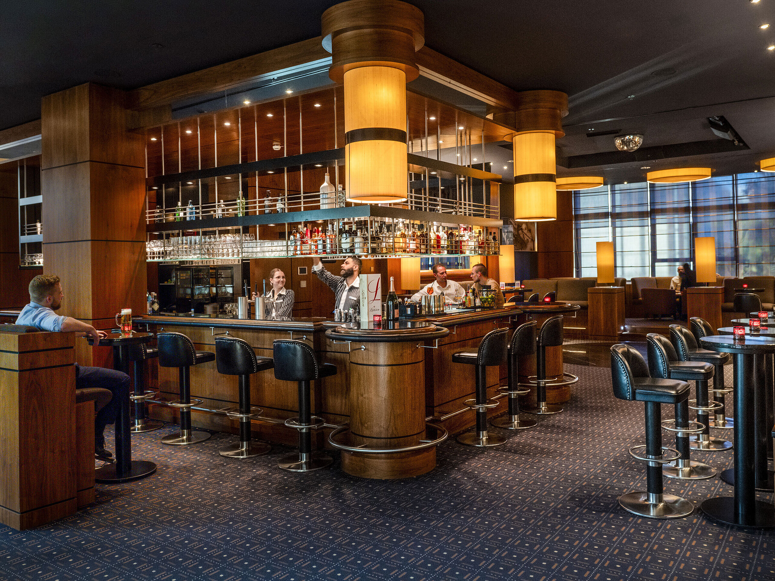 Stilvolle Hotelbar im Maritim Hotel Düsseldorf mit moderner Einrichtung, gemütlicher Atmosphäre und Gästen an der Bar.