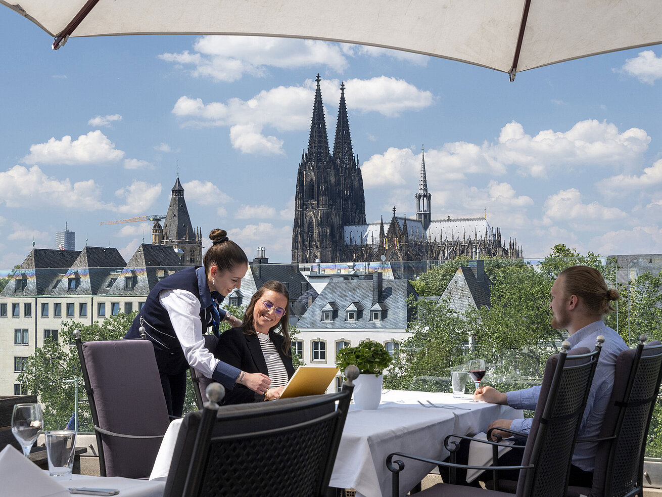Gäste genießen den Service auf der Dachterrasse des Maritim Hotels Köln mit Blick auf den Kölner Dom und die Altstadt.