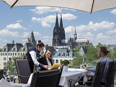 Gäste genießen den Service auf der Dachterrasse des Maritim Hotels Köln mit Blick auf den Kölner Dom und die Altstadt.