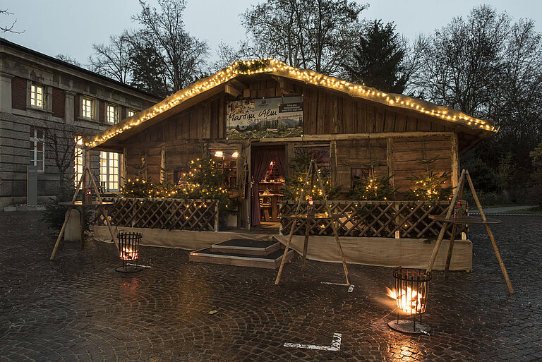 Maritim Alm Stuttgart bei Dämmerung mit Weihnachtsbeleuchtung, Tannen und Feuerkörben vor dem Maritim Hotel