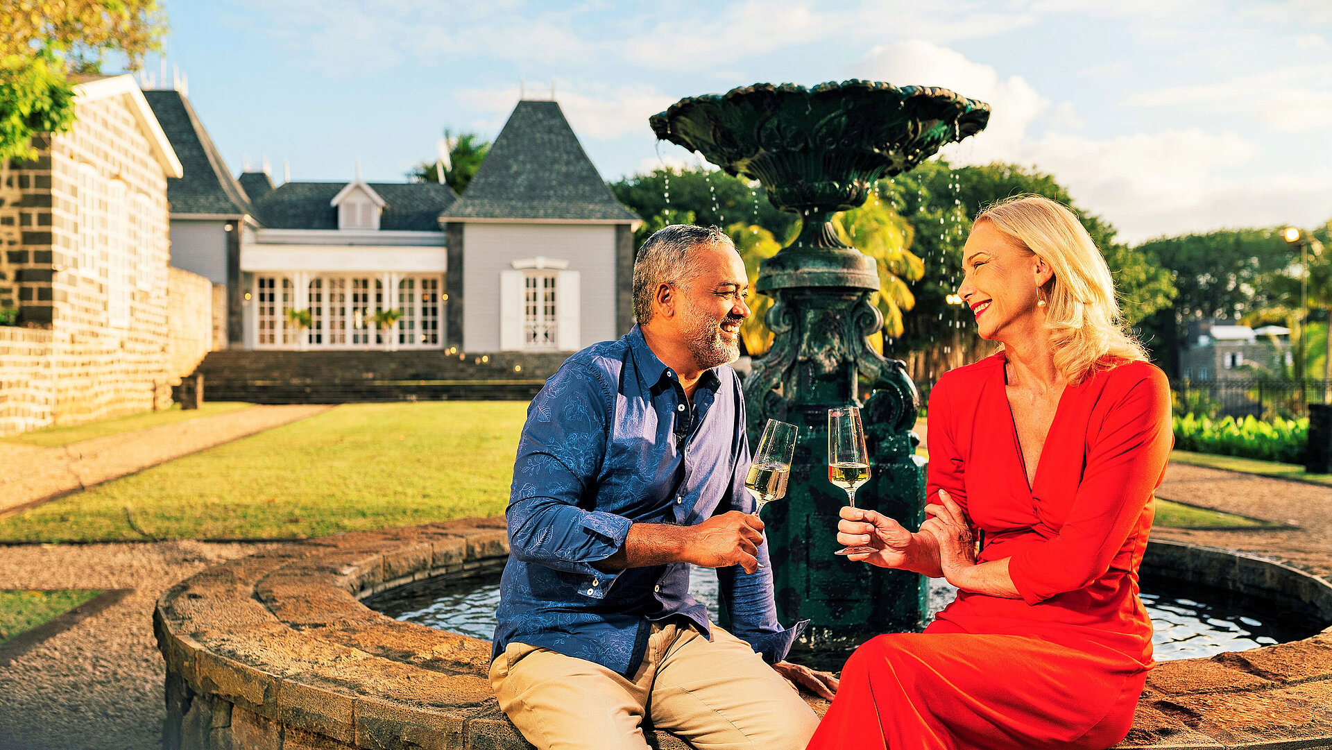 English Garden Paar genießt ein Glas Wein am Brunnen im gepflegten Garten bei Abendstimmung