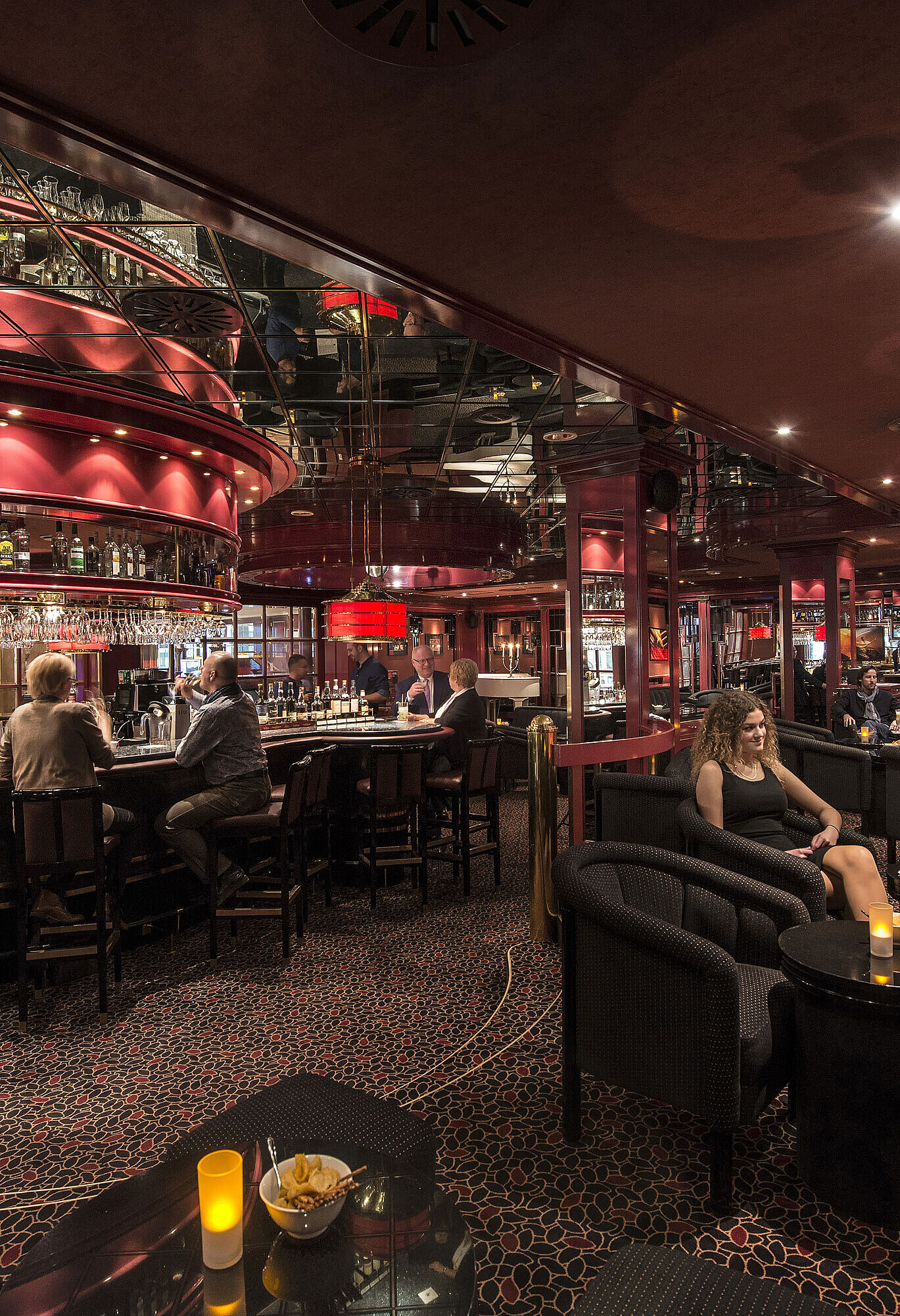 Gäste genießen Drinks in der atmosphärisch beleuchteten roten Hotelbar im Maritim Hotel Stuttgart