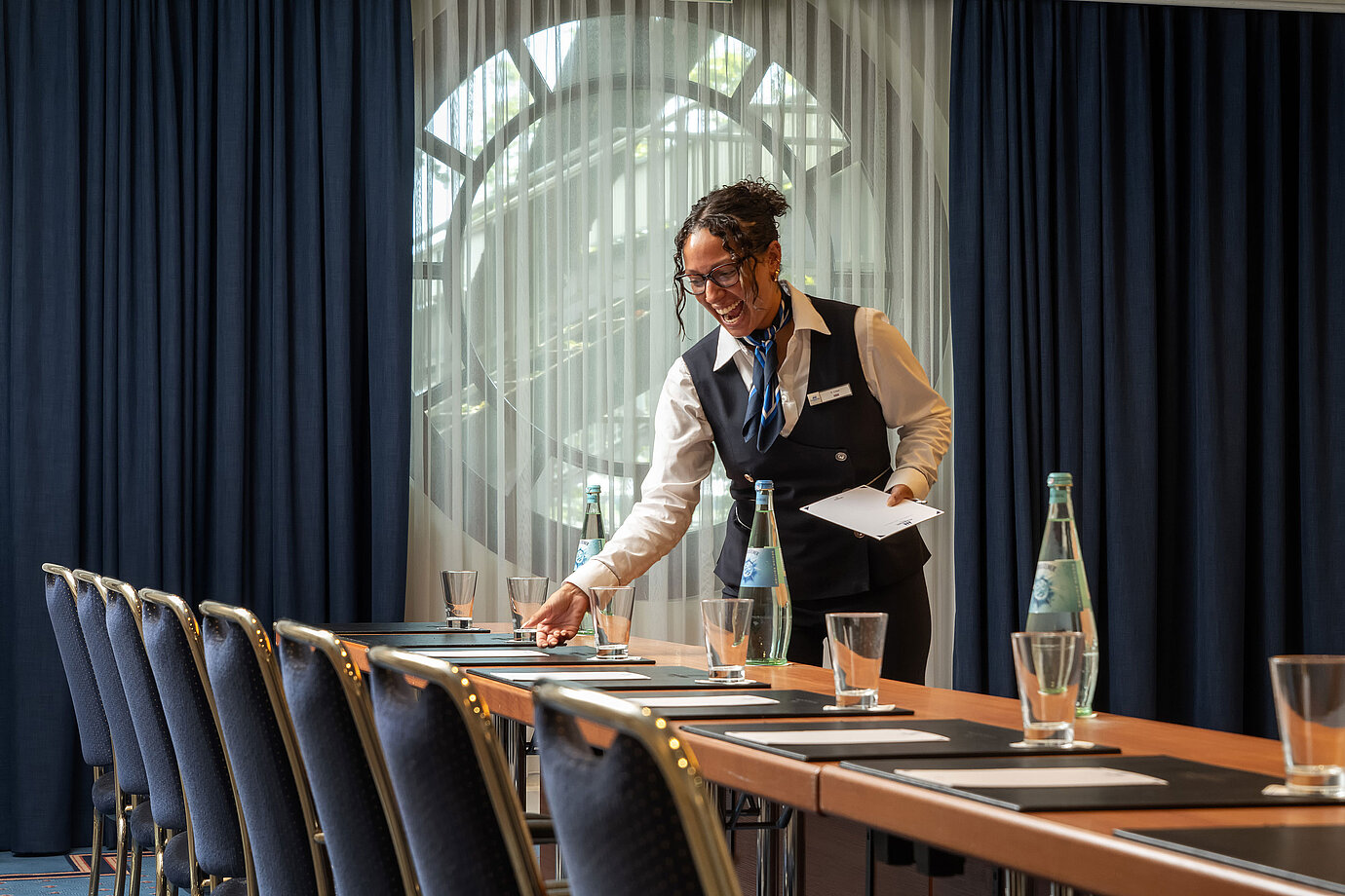 Mitarbeiterin bereitet Tagungsraum im Maritim Hotel Köln mit Lächeln für Gäste vor