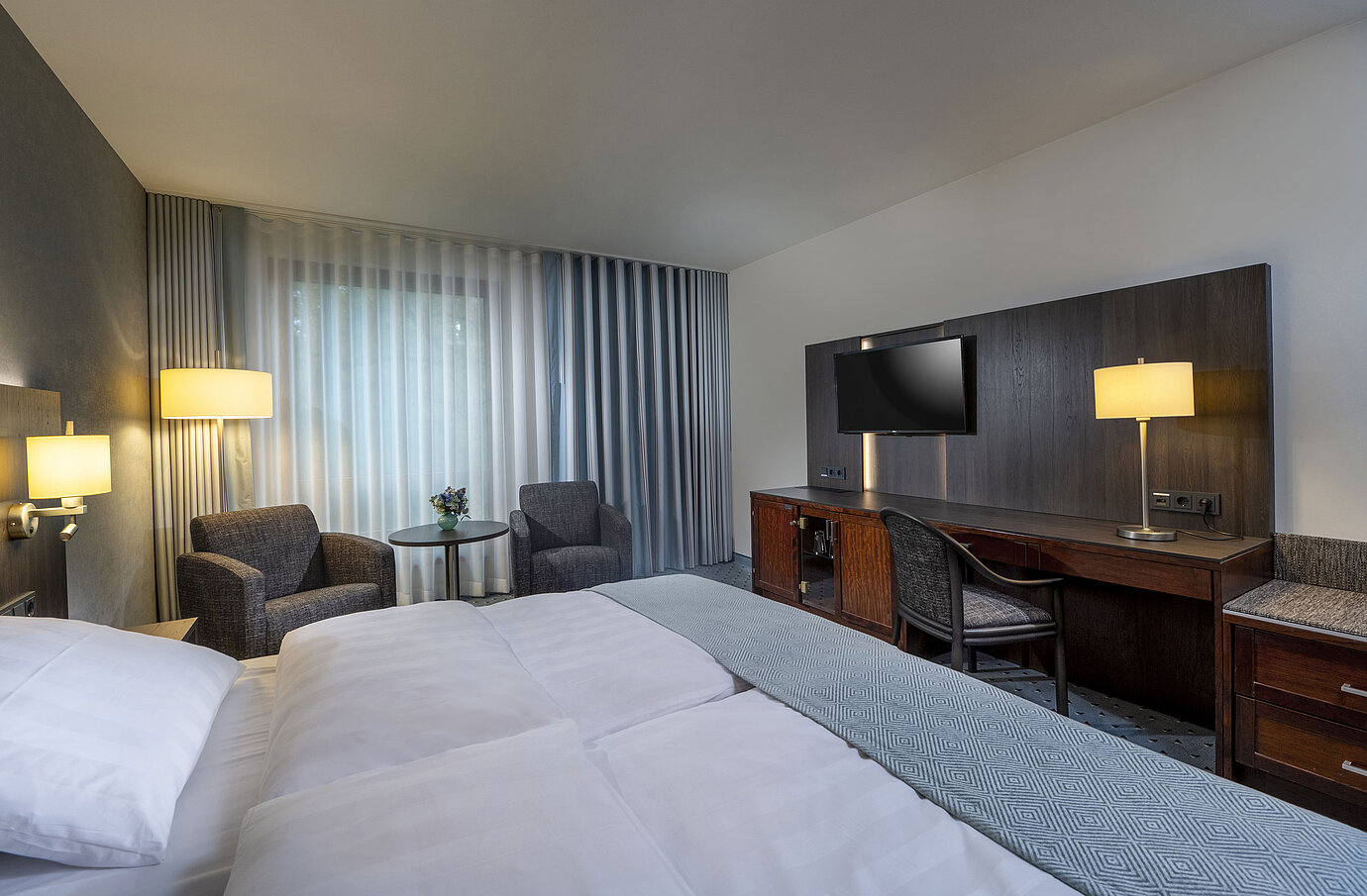Modern eingerichtetes Classic Zimmer mit Schreibtisch, Fernseher, Sitzbereich und komfortablem Bett im Maritim Bremen.