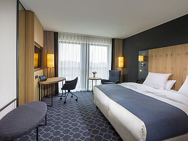 Geräumiges Doppelzimmer im Maritim Hotel Ingolstadt mit Schreibtisch, Sitzbereich und Balkon.