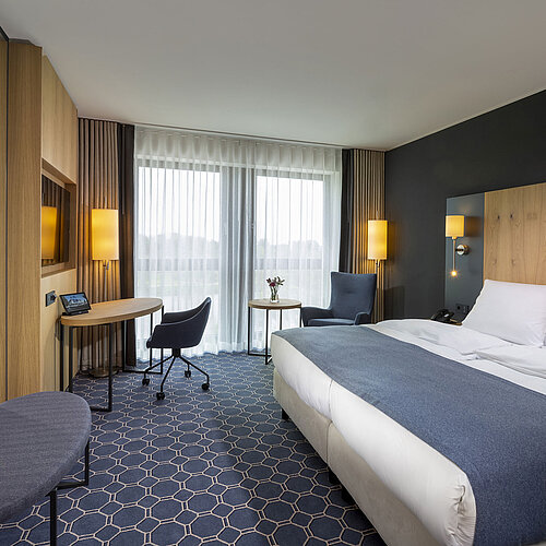 Geräumiges Doppelzimmer im Maritim Hotel Ingolstadt mit Schreibtisch, Sitzbereich und Balkon.