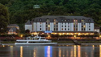 Das Maritim Hotel Königswinter bei Nacht mit stimmungsvoller Beleuchtung und Blick auf den Rhein.