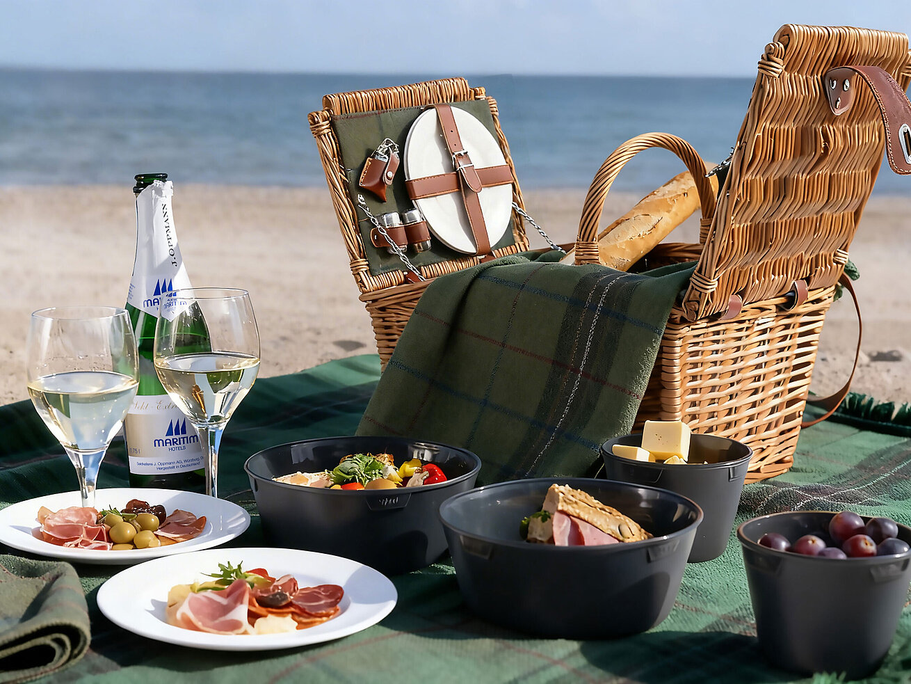 Picknick am Strand Picknickkorb mit Snacks, Obst und Getränken am Strand mit Blick auf das Meer.