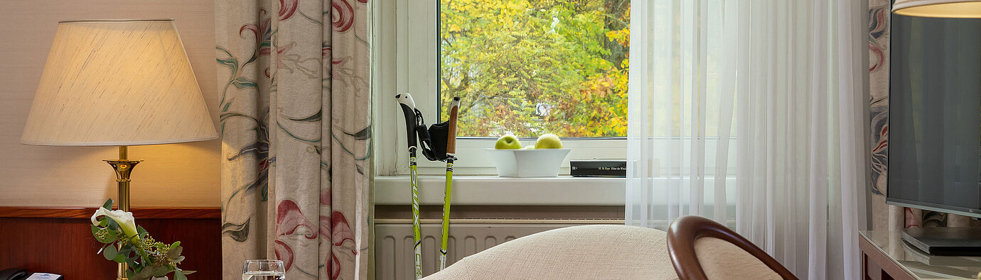 Sitzecke im Classic Einzelzimmer mit Sessel, Tisch, Lampe und Blick durchs Fenster im Maritim Hotel Bad Wildungen.