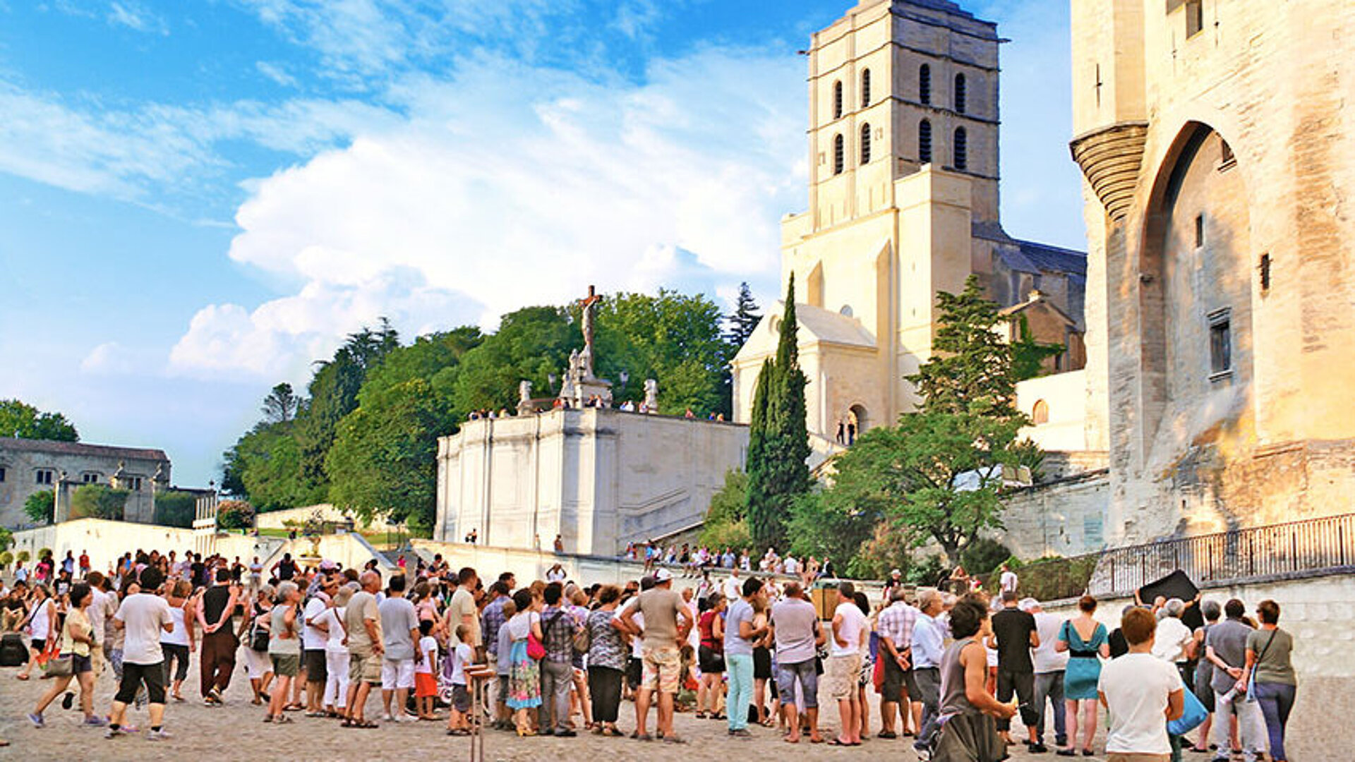 Menschen versammeln sich vor dem historischen Palais des Papes und der Kathedrale beim Festival d'Avignon.
