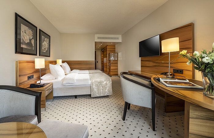 Komfortzimmer im Maritim Hotel Bad Homburg mit Doppelbett, stilvollem Holzdekor und moderner Ausstattung.
