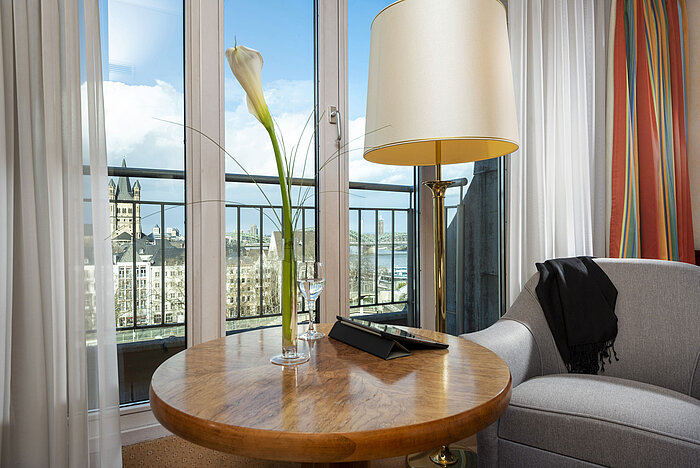 Classic Zimmer im Maritim Hotel Köln mit Ausblick auf den Rhein, eine Sitzecke und ein Tisch mit eleganter Dekoration.