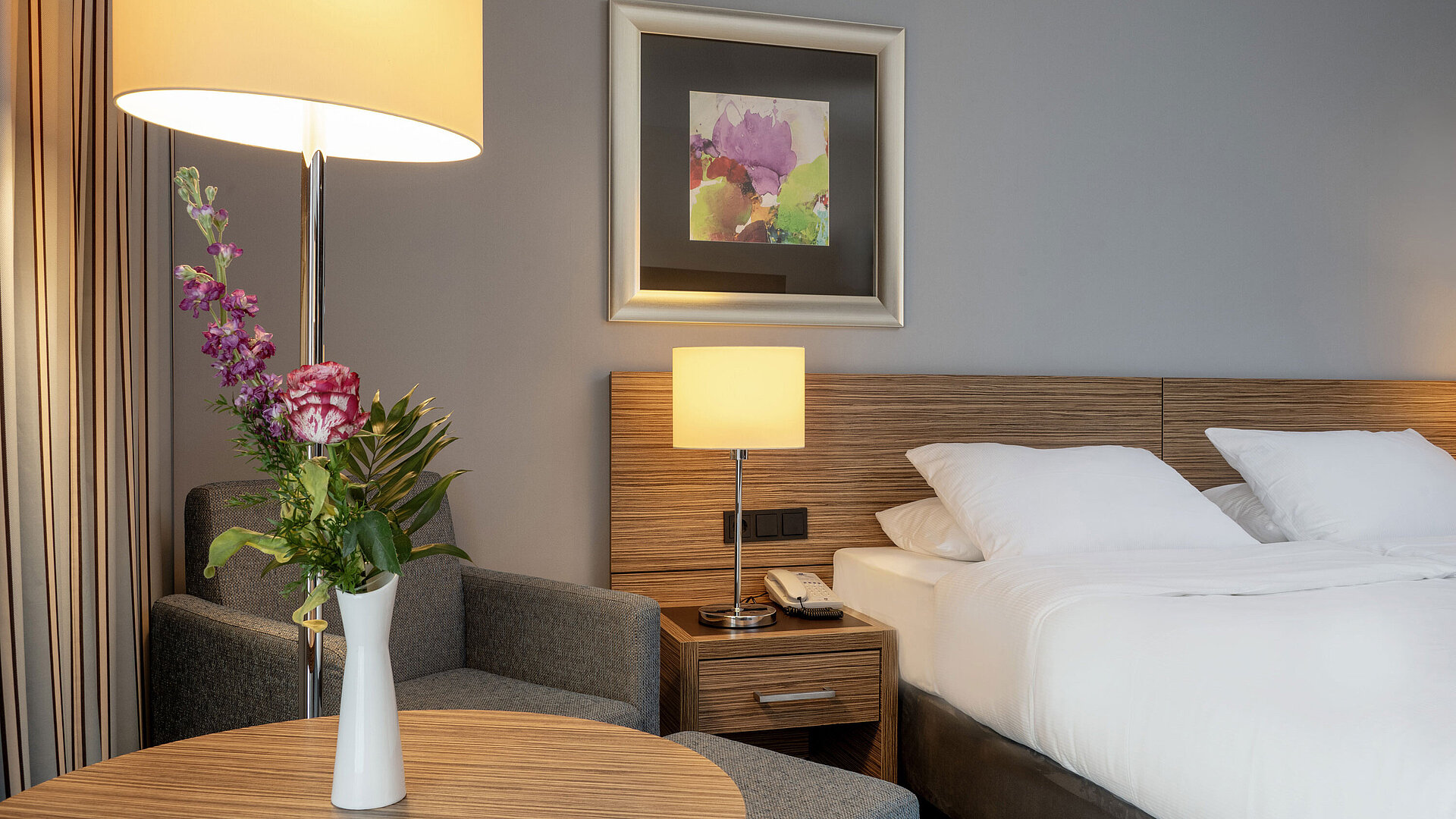 Gemütliche Sitzecke mit Blumenvase neben dem komfortablen Bett im Superior Zimmer des Maritim Hotel Darmstadt
